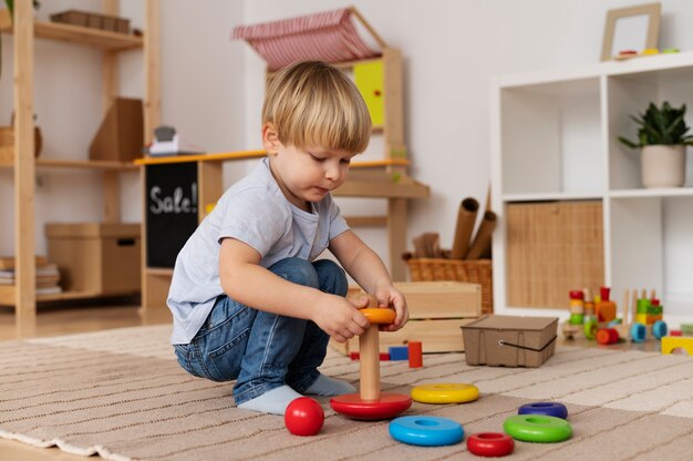 Niño lindo de tiro completo jugando con juguete de madera