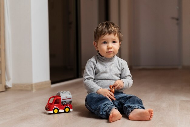 Niño lindo de tiro completo sentado en el piso