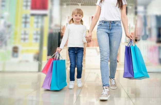 Niño y madre con coloridos bolsos de compras en la tienda.