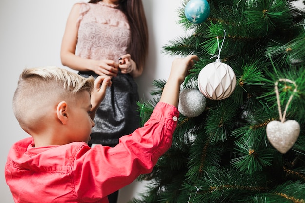 Niño y madre decorando árbol de navidad