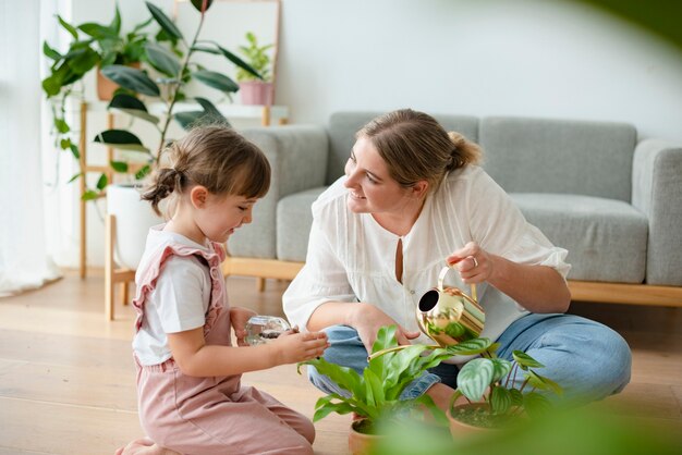 Niño con mamá regando plantas en macetas en casa