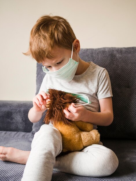 Niño con máscara jugando con juguetes en casa