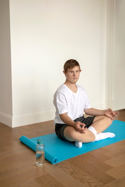 Foto gratuita niño meditando en la estera de yoga tiro completo