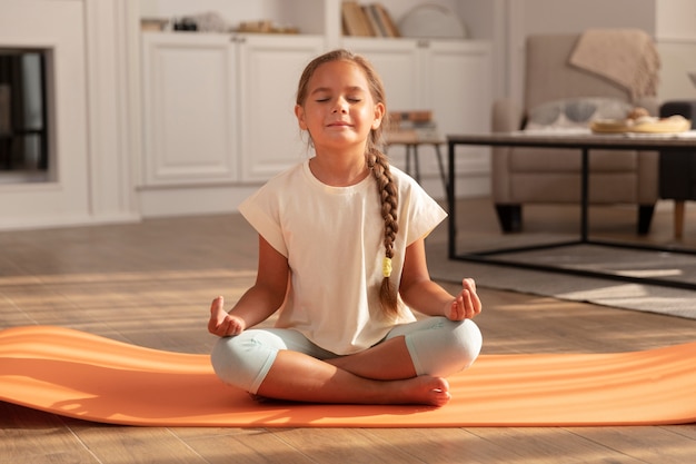 Niño meditando sobre la estera de yoga full shot