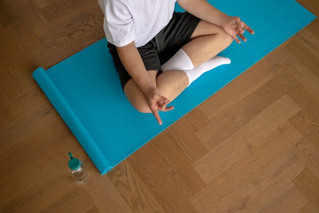Niño meditando en la vista superior de la estera de yoga