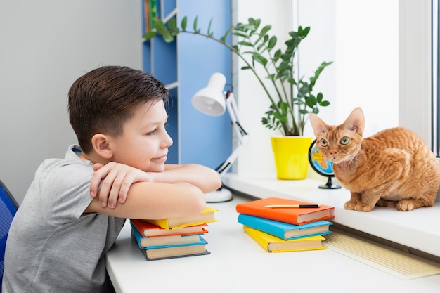 Niño en la mesa con pila de libros