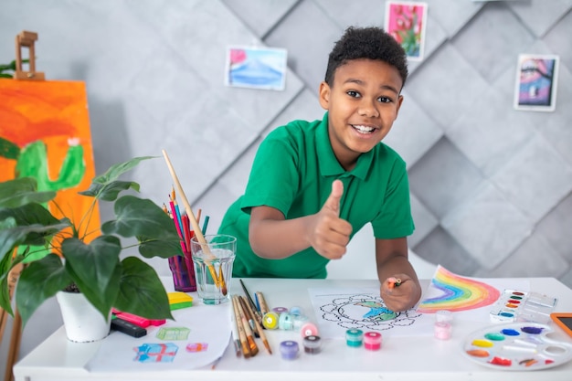 Niño mirando a la cámara mostrando el signo de ok del dedo