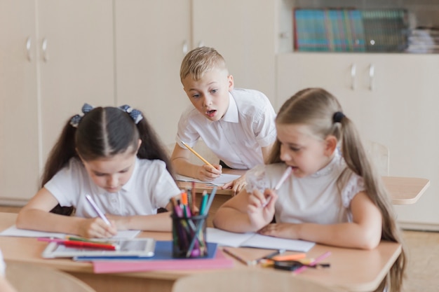 Niño mirando furtivamente en cuadernos de chicas