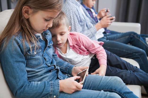 Niño mirando a la hermana con smartphone