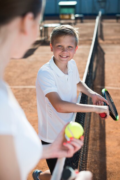 Niño mirando a la mujer en el campo de tenis