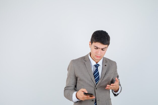 Niño mirando el teléfono, estirando la mano en traje formal