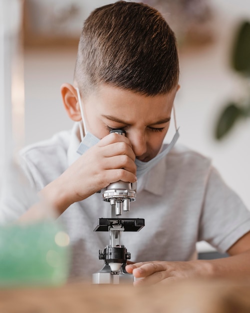 Foto gratuita niño mirando a través de un microscopio