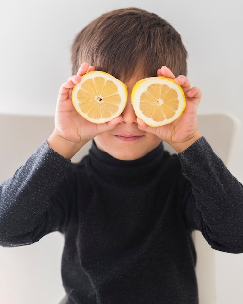 Foto gratuita niño con mitades naranjas sobre los ojos