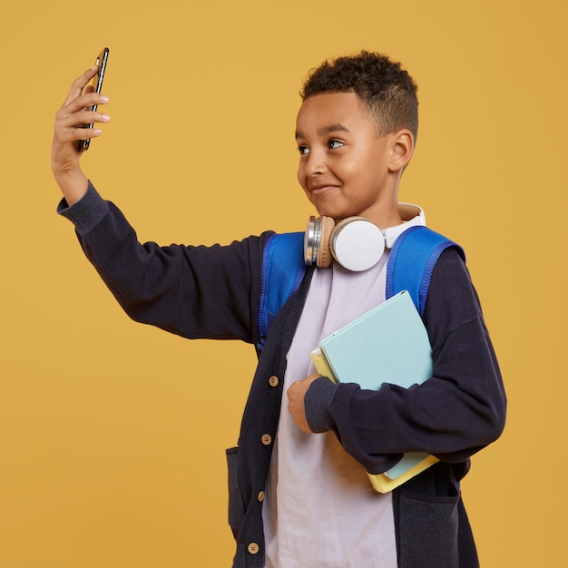 Foto gratuita niño con mochila azul tomando una foto del uno mismo