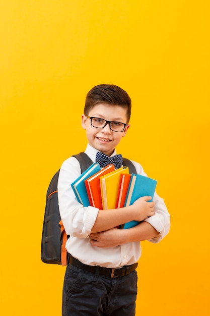 Niño con mochila con pila de libros