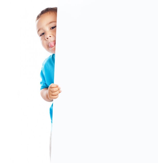 Niño mostrando la lengua y sujetando un cartel en blanco