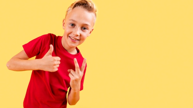 Niño mostrando signo bien y paz con espacio de copia