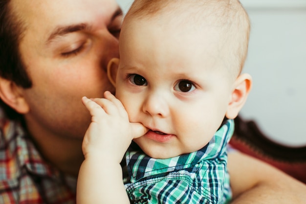 Niño se muerde el dedo mientras que su padre lo besa