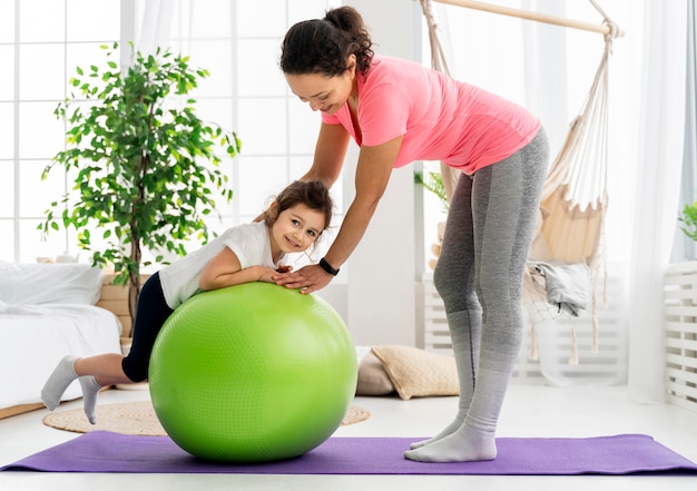 Foto gratuita niño y mujer entrenando con pelota de gimnasia