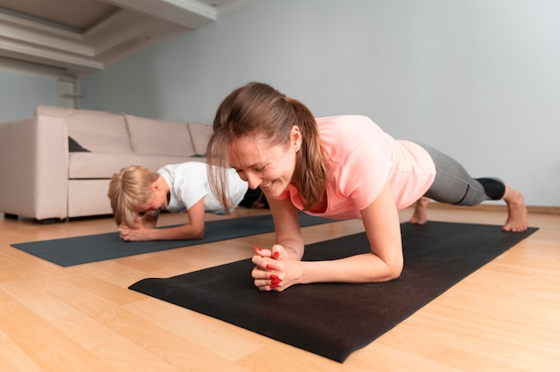 Niño y mujer de tiro completo con colchonetas de yoga