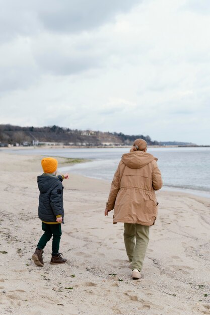 Niño y mujer en tiro completo junto al mar