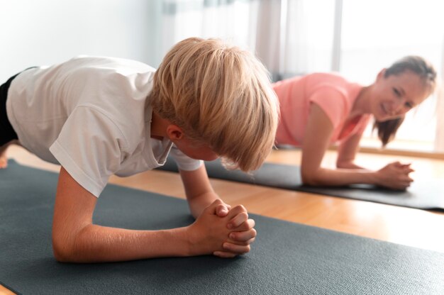 Niño y mujer de tiro medio con colchonetas de yoga