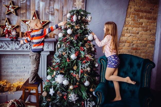 El niño y la niña bonita decorar un árbol de Navidad