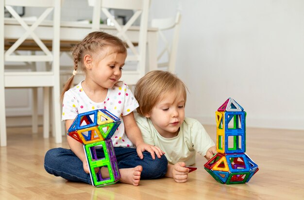 Niño y niña en casa jugando con juguetes juntos