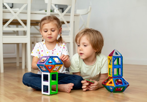 Niño y niña en casa jugando con juguetes