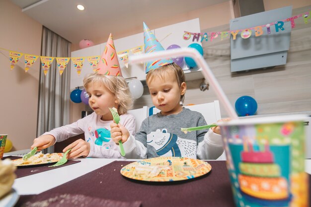 Niño y niña comiendo pastel de cumpleaños