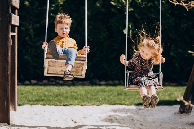 Niño y una niña divirtiéndose balanceándose