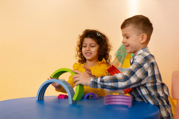 Niño y niña jugando en el interior con juguetes ecológicos