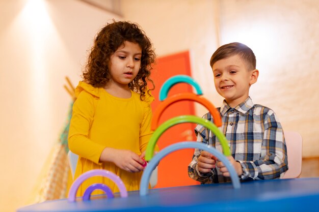 Niño y niña jugando en el interior con juguetes ecológicos