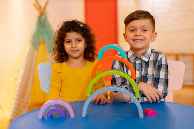 Niño y niña jugando en el interior con juguetes ecológicos