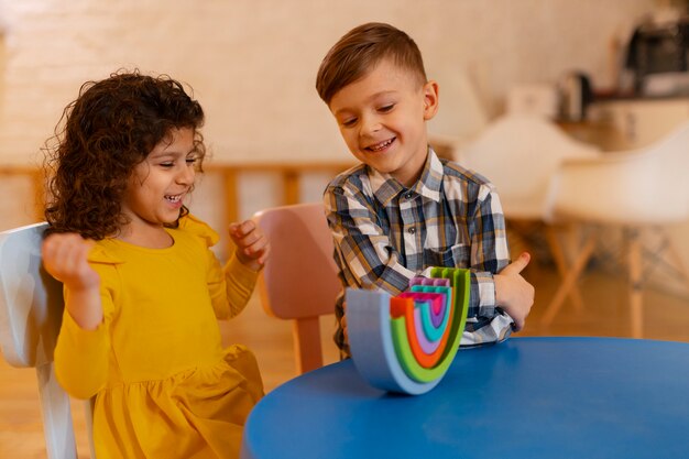 Niño y niña jugando en el interior con juguetes ecológicos