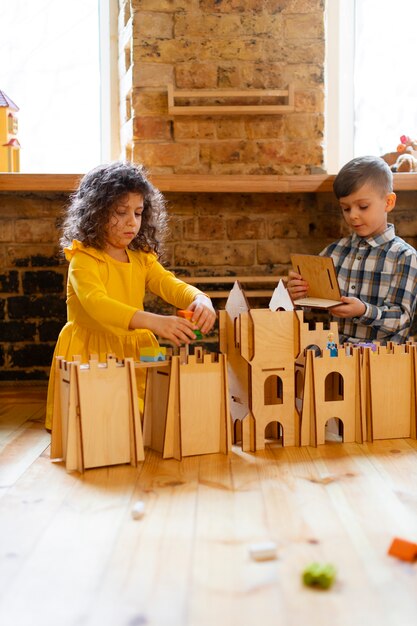 Niño y niña jugando en el interior con juguetes ecológicos