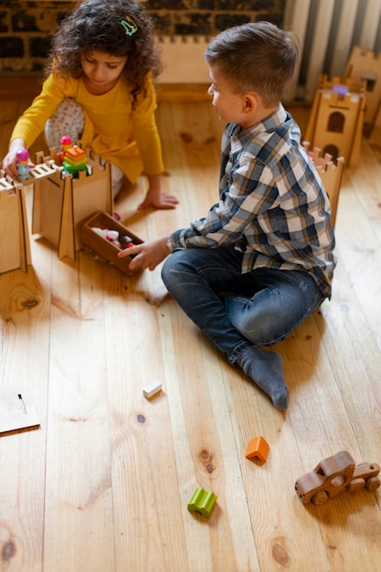 Niño y niña jugando en el interior con juguetes ecológicos