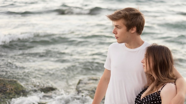 Niño y niña mirando a otro lado en la playa con espacio de copia