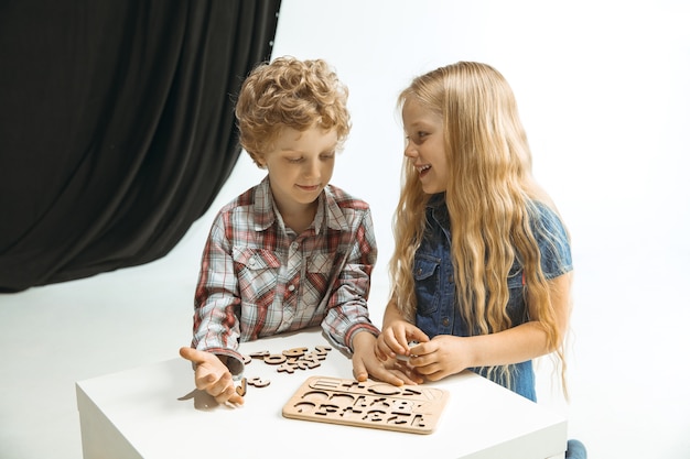 Niño y niña preparándose para la escuela después de un largo receso de verano. De vuelta a la escuela. Pequeños modelos caucásicos jugando juntos en el espacio blanco y negro