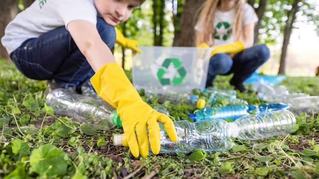 Niño y niña en la recolección de basura plástica en un parque