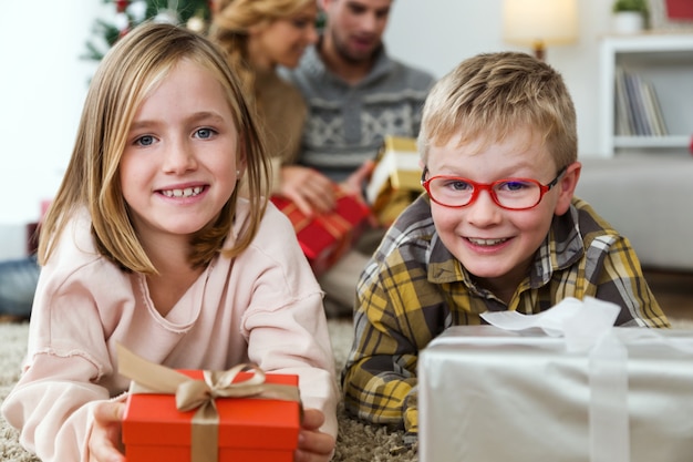 Niño y niña con un regalo rojo y uno plateado