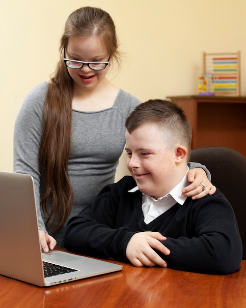 Foto gratuita niño y niña con síndrome de down mirando portátil