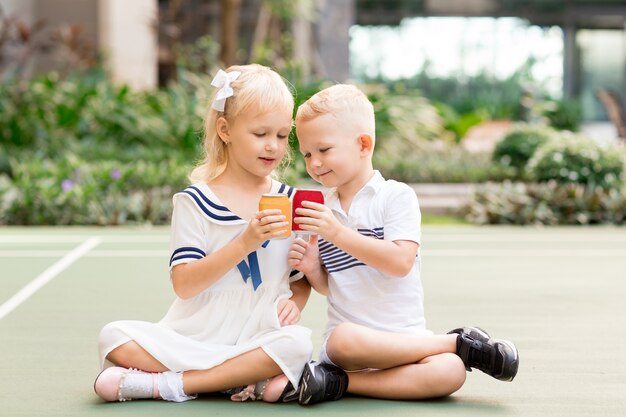 Niño y niña sosteniendo bebidas latas al aire libre
