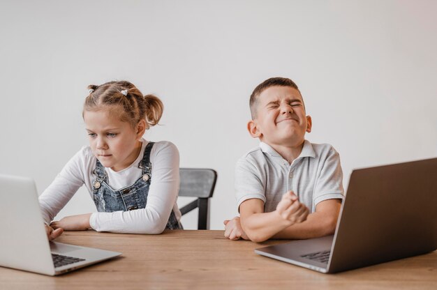 Niño y niña usando computadoras portátiles en la escuela