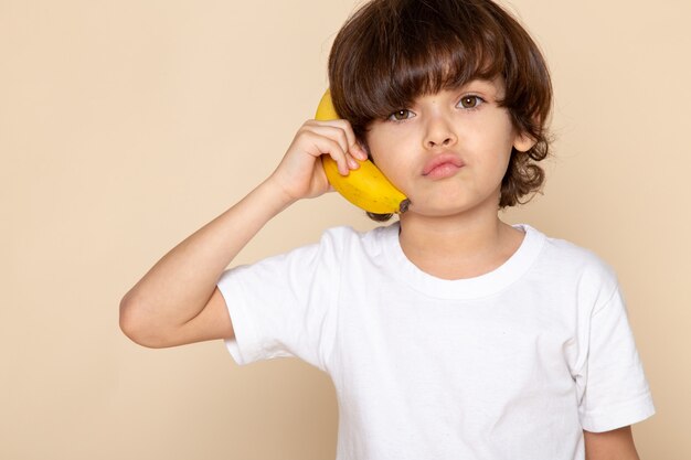 niño niño lindo adorable en camiseta blanca con plátano en rosa