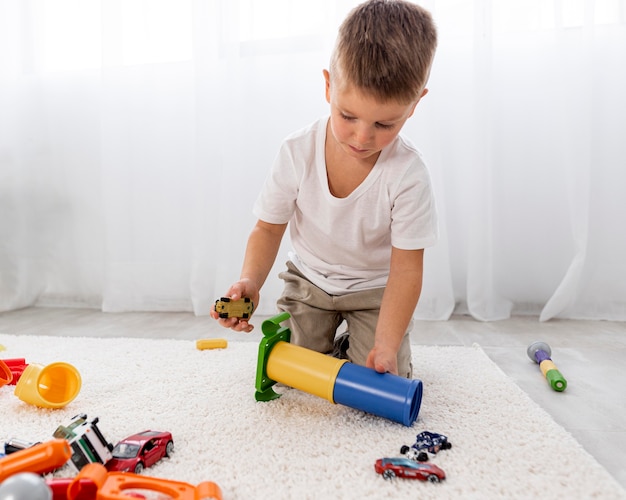 Foto gratuita niño no binario jugando con un juego de coches.