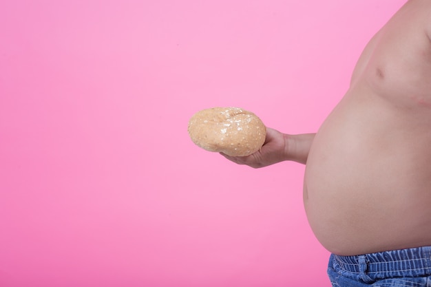 Foto gratuita niño obeso que tiene sobrepeso sobre un fondo rosa.