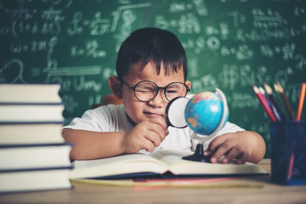 niño observando o estudiando el modelo de globo educativo en el aula.