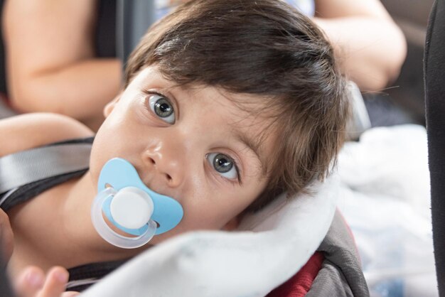 Niño con ojos azules sentado en el asiento del bebé