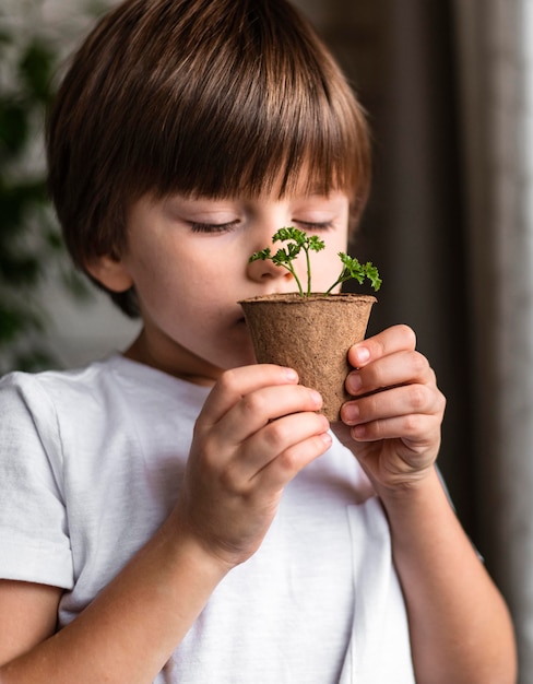 Foto gratuita niño oliendo plantas en maceta en casa